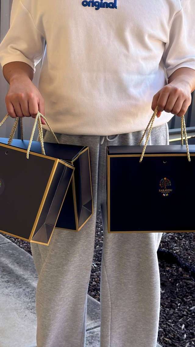 Happy customer holding two Sarayou Threads gift bags with a festive season order